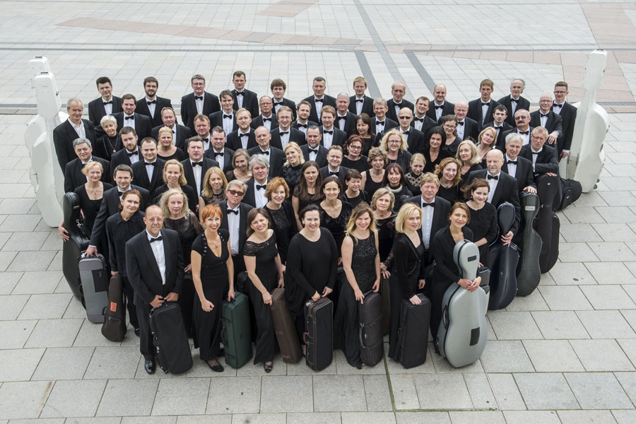Duża grupa muzyków stojących z instrumentami 